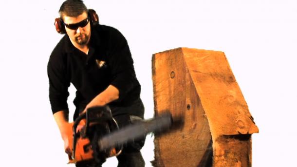 A man with a chainsaw shaping a large block of wood.